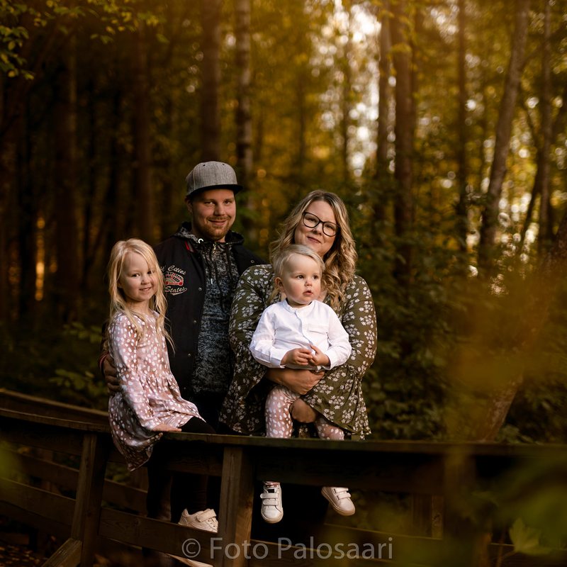 Perhe sillalla syksy-metsässä, golden hour